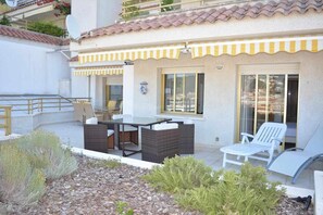 Une terrasse avec des meubles d’extérieur, une table et des chaises.