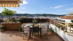 Une terrasse avec une table dressée pour le petit-déjeuner, offrant une vue sur le paysage urbain.