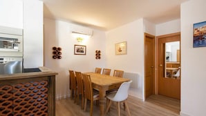 Un coin repas avec une table et des chaises en bois, une cuisine équipée d’appareils électroménagers Bosch et une porte donnant sur une autre pièce.