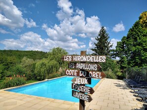A wooden signpost with directional arrows pointing to various amenities including a pool, games, and a cafe. - Les Papillons 4/6, Pool, Balcony, Garden & Courtyard, Top Location & Activities (Domme)