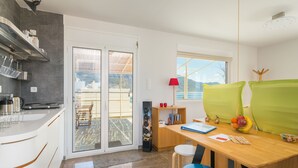 Una cocina moderna con un ventanal grande, un comedor con mesa y sillas, y vistas al exterior.