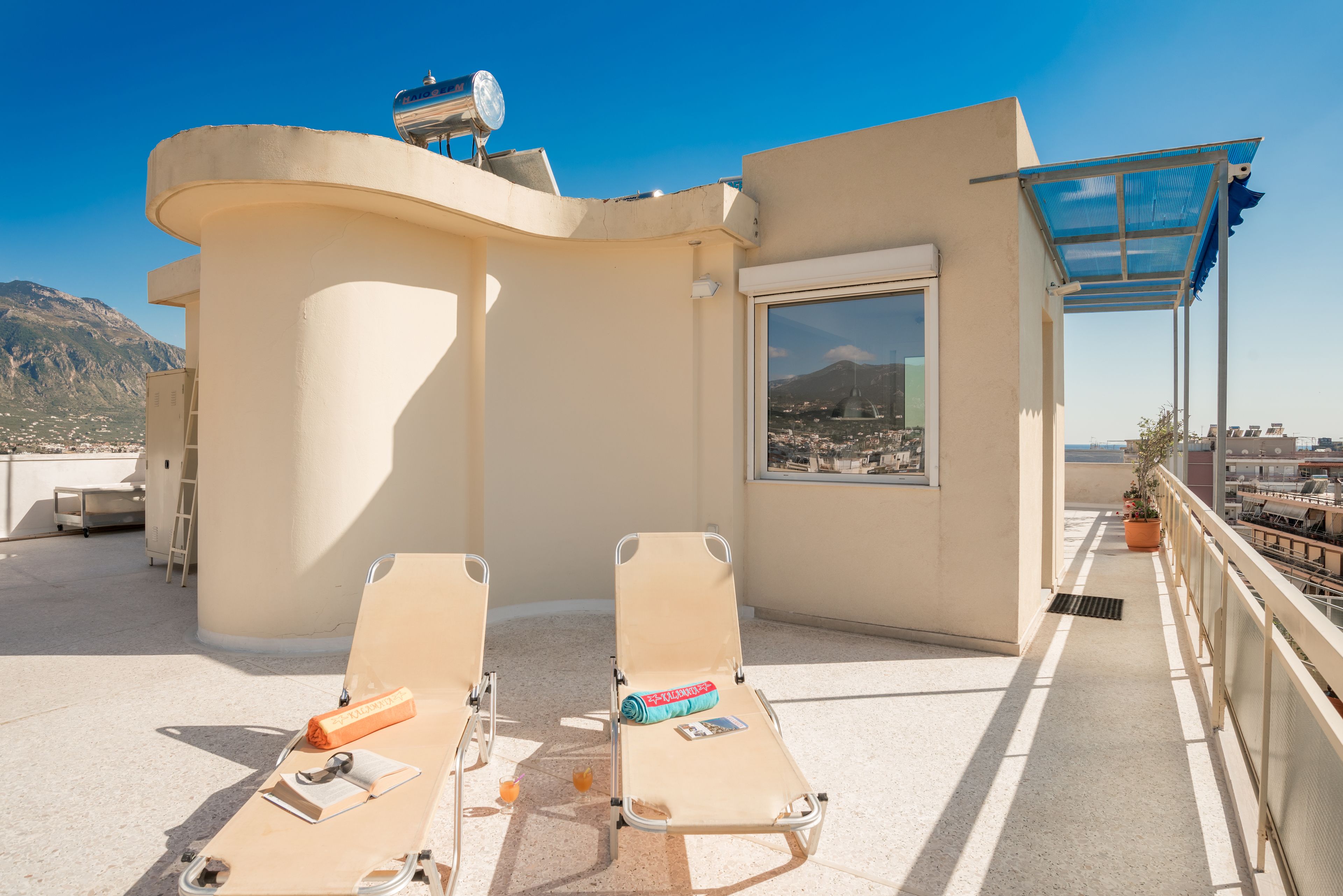 Une terrasse sur le toit avec deux chaises longues, une petite table et un pot de fleurs.