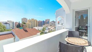 Un balcon avec une table et des chaises, donnant sur un paysage urbain composé de différents bâtiments.