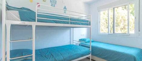 A bunk bed room with a window, white walls, and a ceiling fan.