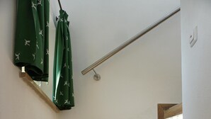 Eine Holztreppe mit Handlauf und einem grünen Vorhang.