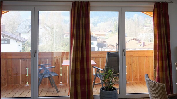 Ein geräumiger Raum mit einer großen Schiebeglastür, die auf eine Terrasse im Freien führt.