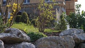 Ein Holzhaus mit einem Balkon, umgeben von Steinen und Pflanzen.