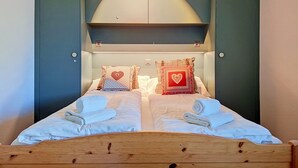 Una cama doble con dos almohadas, cabecera de madera y techo curvo.