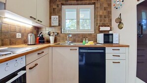 Une cuisine compacte équipée d’un lave-vaisselle, d’une cuisinière, d’un four à micro-ondes et d’une fenêtre située au-dessus de l’évier.