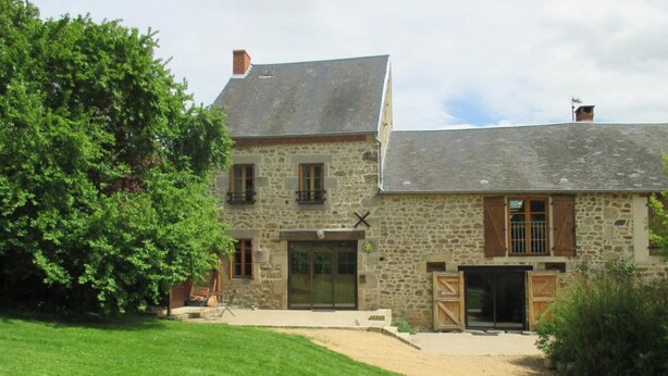 A stone house with a large front door, a small porch, and a well-maintained lawn. - Large stone house with enclosed garden, pets allowed (Marcillat-en-Combraille)