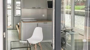 Une cuisine compacte avec une chaise blanche, un petit plan de travail et une vue sur une étendue d’eau par la fenêtre.