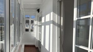 A corridor with white walls and large windows, leading to a room with a bed. - GREAT CENTRAL HOUSE TIAS LANZAROTE (Tías)