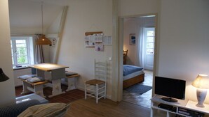 A cozy room with a bed, a desk, a chair, a television, and a lamp. -  New: Apartment Mühlenblick, balcony and garden, WiFi (Struckum)