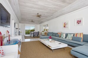 A spacious living room with a large sofa, a coffee table, and a dining area with a table and chairs.