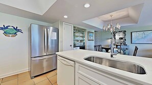 A modern kitchen with stainless steel appliances, a white countertop, and a chandelier. - Marshfront 14E Beautiful View, Beach & Pool! (Pawleys Island)