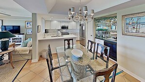 A modern kitchen with white cabinets, a central island, and a chandelier. - Marshfront 14E Beautiful View, Beach & Pool! (Pawleys Island)