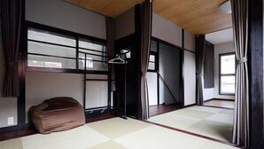 Een traditionele Japanse kamer met tatami vloerbedekking, schuifdeuren en een hangende kledingrek.