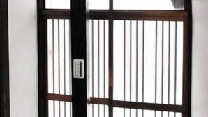 Een traditionele Japanse kamer met tatami vloeren, een shoji schuifdeur en een plafond met een ingebouwde verlichtingsarmatuur.