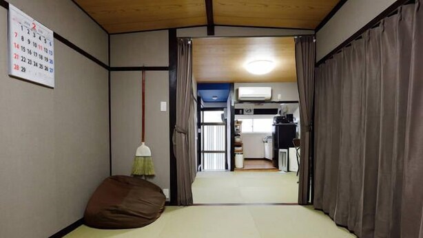 Een traditionele Japanse kamer met tatami vloerbedekking, een futonbed, een shoji schuifwand en een kalender aan de muur.