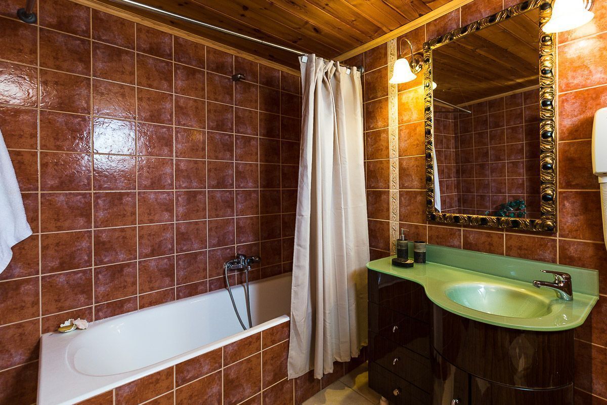 A bathroom with a bathtub, a green sink, and a mirror with an ornate frame.