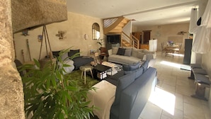 A spacious living area with a sofa, coffee table, and plants. A staircase leads to a dining area with a table and chairs. - Country house by the sea - Perros Guirec on the Pink Granite Coast (Saint-Quay-Perros)