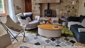 A cozy living room with stone walls, a fireplace, and comfortable seating including a sofa, chairs, and a round coffee table. - Country house by the sea - Perros Guirec on the Pink Granite Coast (Saint-Quay-Perros)