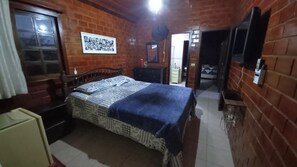 Ein Schlafzimmer mit Bett, Kommode, Spiegel und einer Tür zu einem weiteren Raum.