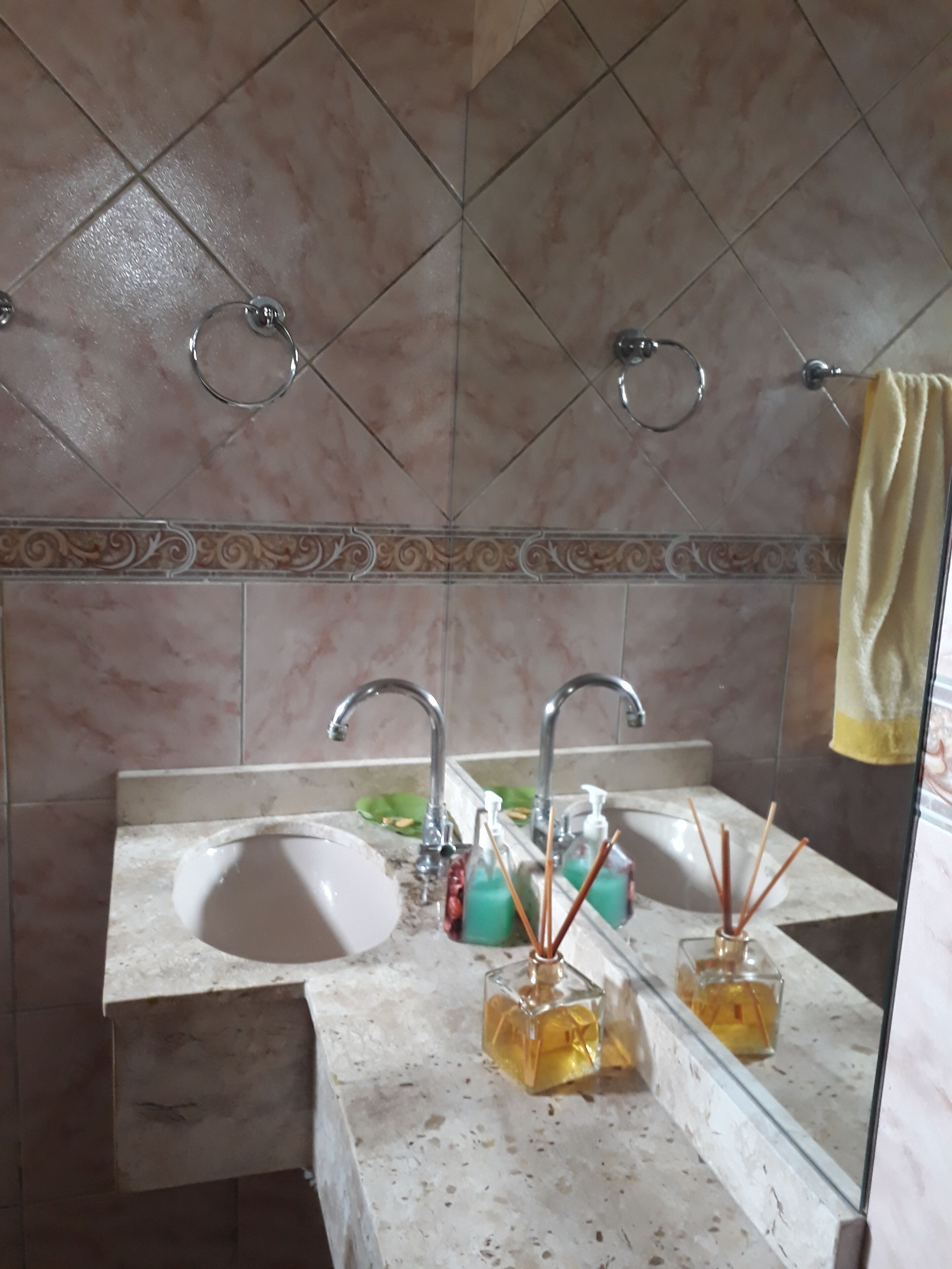 Un baño con dos lavamanos, un espejo y un perchero para toallas.