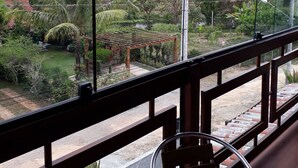 Une vue depuis un balcon doté d’une balustrade en bois, d’une chaise et d’une table recouverte d’une nappe colorée.