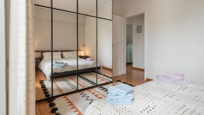 Een slaapkamer met een bed, een spiegel, een nachtkastje en een vloerkleed.