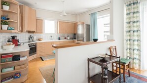Een moderne keuken met houten kastjes, een centraal eiland en een eethoek met tafel en stoelen.