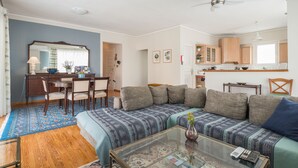 Een woonkamer met een bank, salontafel en een eethoek met stoelen en een tafel.
