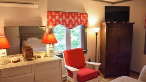 Ein Schlafzimmer mit einem Bett, einem roten Sessel, einer Kommode, einem Fernseher und einem Schrank.