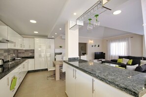 Een moderne keuken met witte kasten, een marmeren aanrecht en een ingebouwde oven.