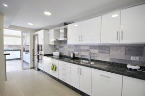 Een moderne keuken met witte kasten, een granieten aanrecht en een roestvrijstalen spoelbak.