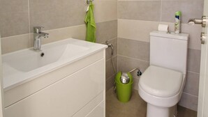 Un baño con lavamanos, espejo e inodoro blancos.