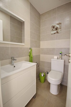 Un bagno con lavandino, specchio e servizi igienici bianchi.