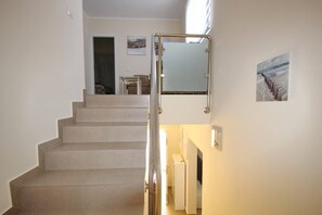 Een trap die uitkomt op een plateau met een leuning, een spiegel aan de muur en een lijst met een afbeelding.
