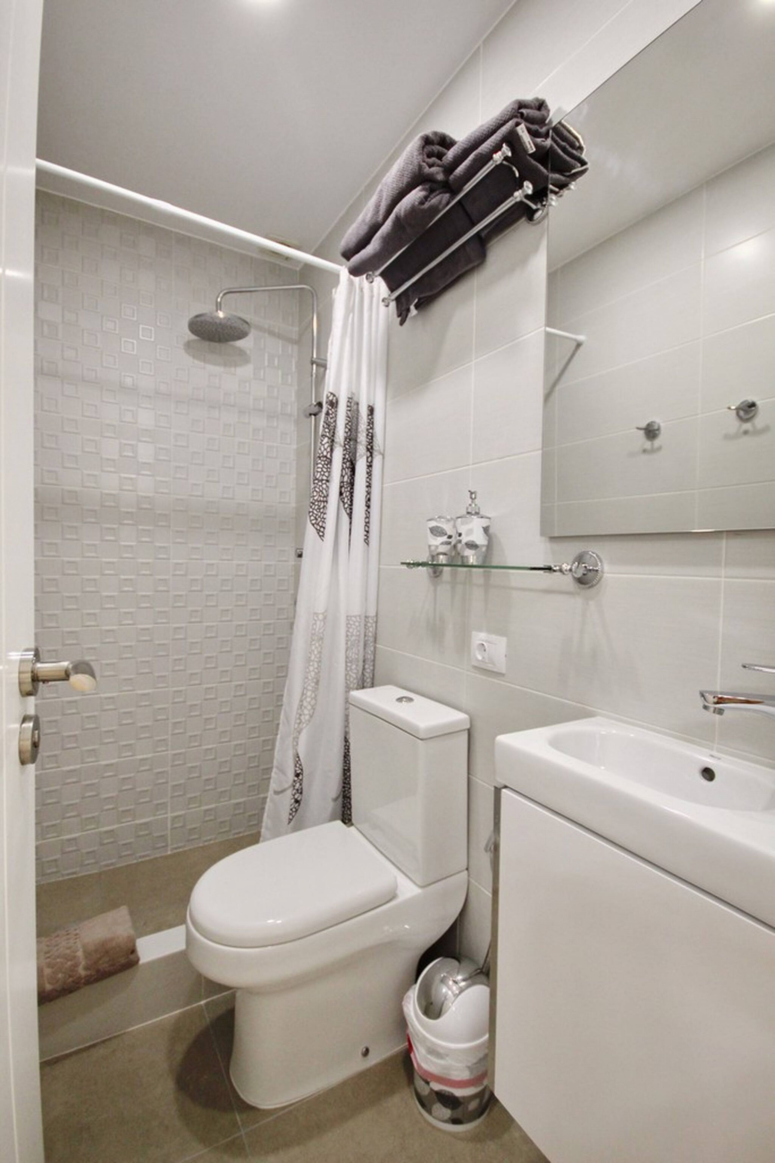 A bathroom with a toilet, shower, and sink.