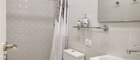 A bathroom with a toilet, shower, and sink.