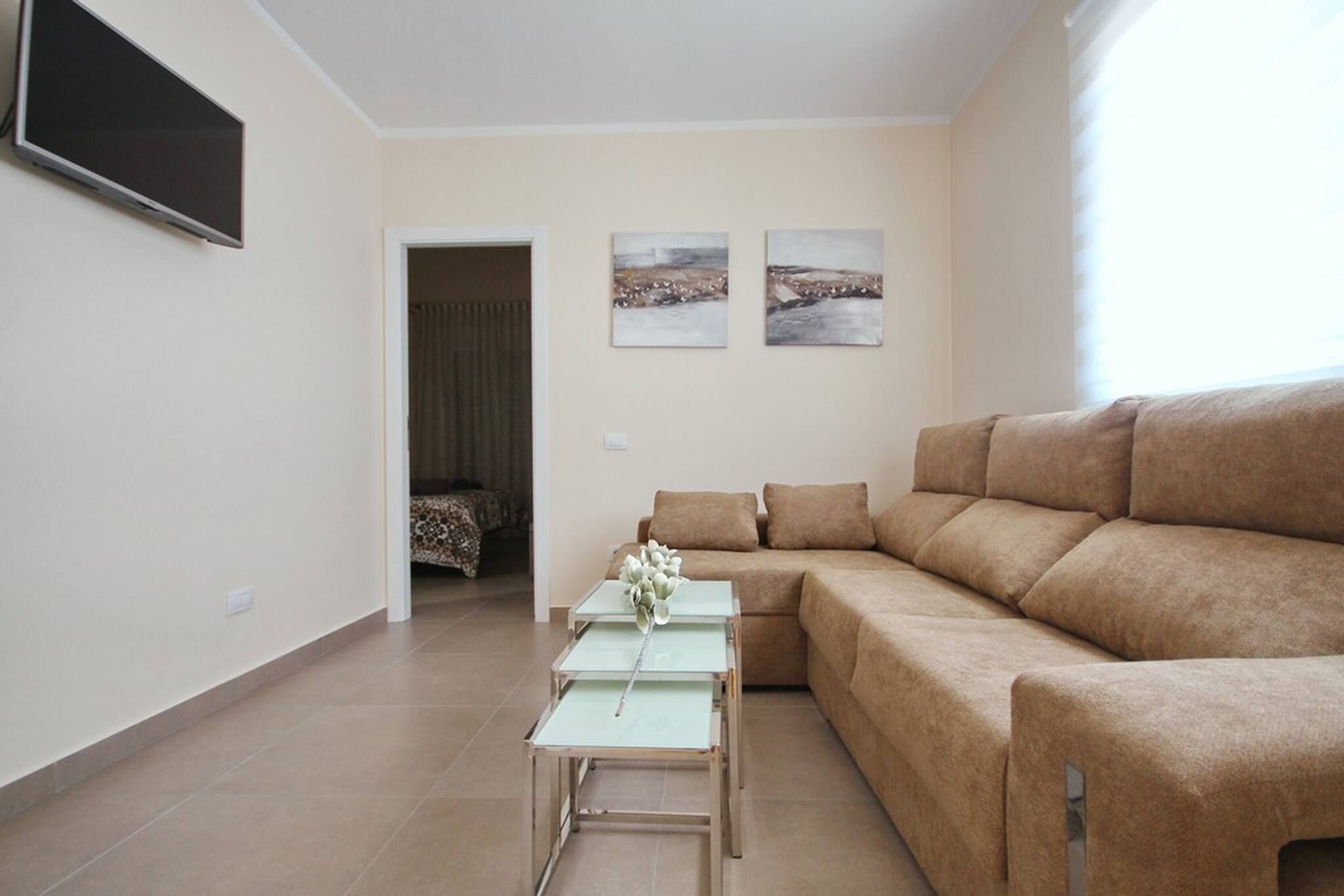 Un salon moderne avec un canapé d’angle, une table basse et deux tableaux accrochés au mur.