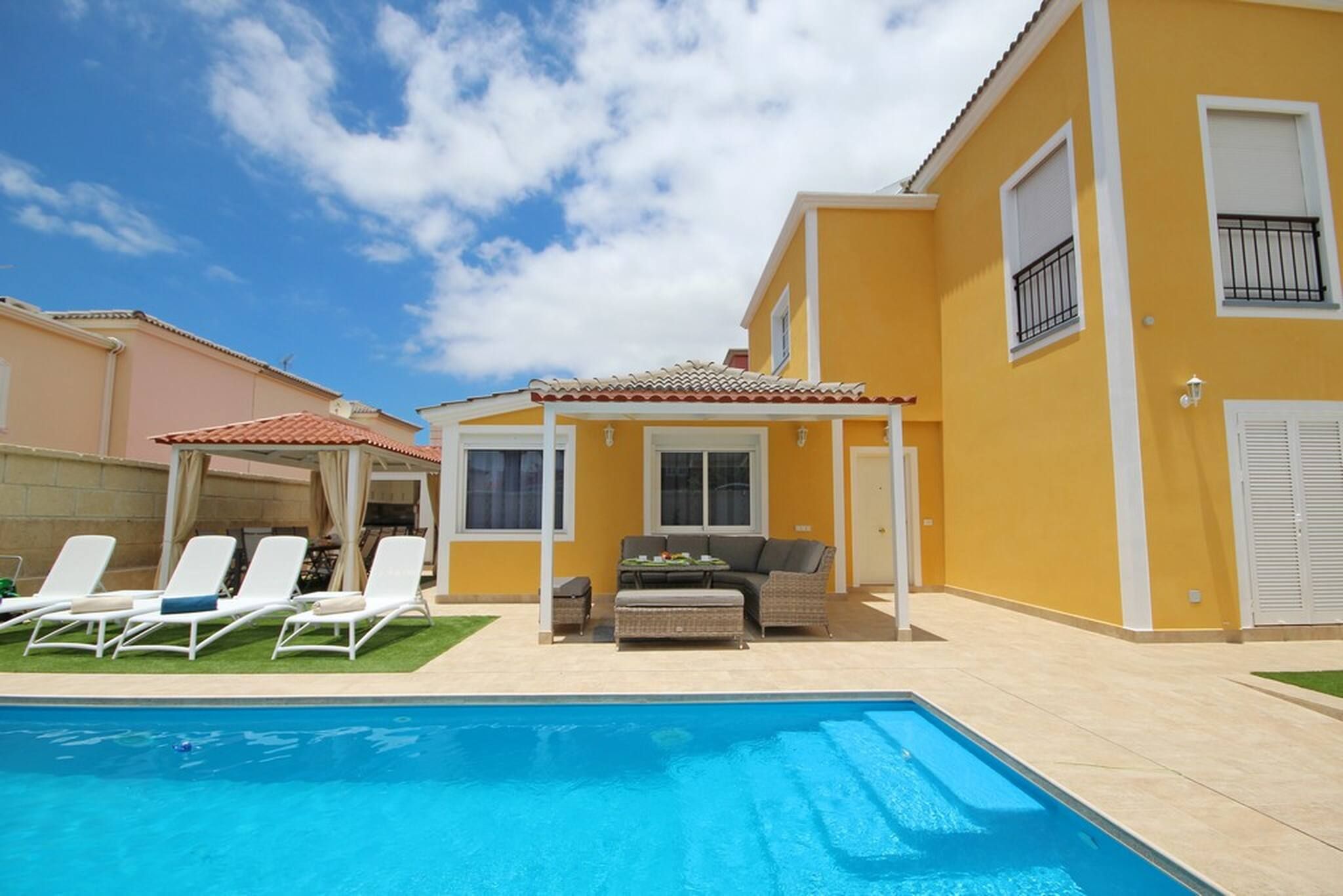 Una propiedad residencial con piscina, mobiliario exterior y un patio cubierto.