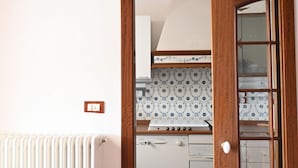 A kitchen with a white stove, a white oven, and a patterned backsplash. - N096 - Numana, two-room villa with garden and sea view (Sirolo)
