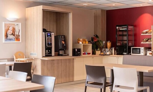 A modern cafe with wooden furniture, a coffee machine, and a microwave. - ACE Hôtel Paris Sud Villabe (Villabe)