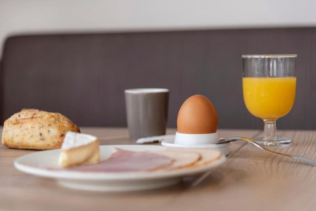 A breakfast setting with a plate of food, a glass of orange juice, a muffin, and a cup.