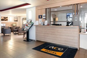 Zona de recepción de hotel con mostrador, área de estar y carteles informativos.