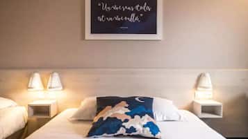 Een hotelkamer met een bed, twee bedlampen, een muisbrief en een decoratief kussen.