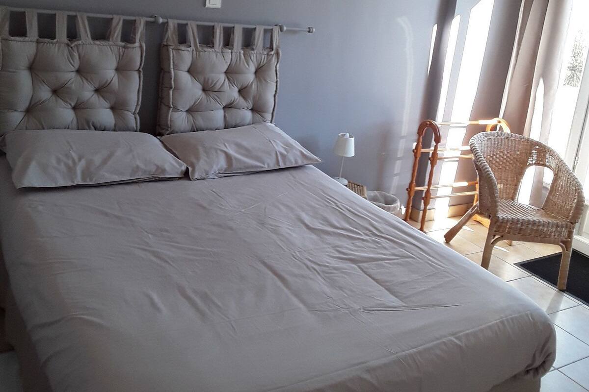 A bedroom with a large bed, a chair, and a window with curtains.