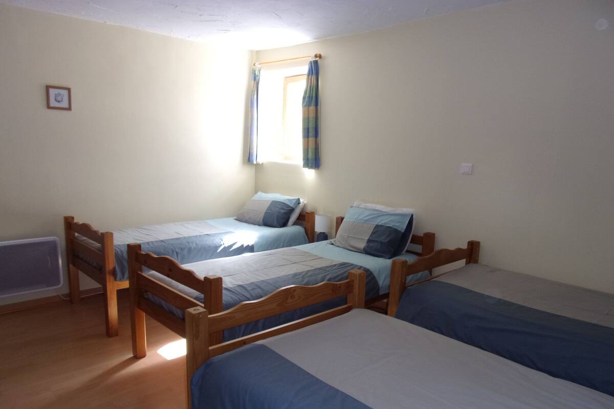 A room with two wooden beds, a window with curtains, and a radiator.