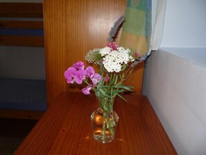 A wooden table with a clear glass vase containing a bouquet of flowers. - La Chouette (Sainte-Anne-Saint-Priest)